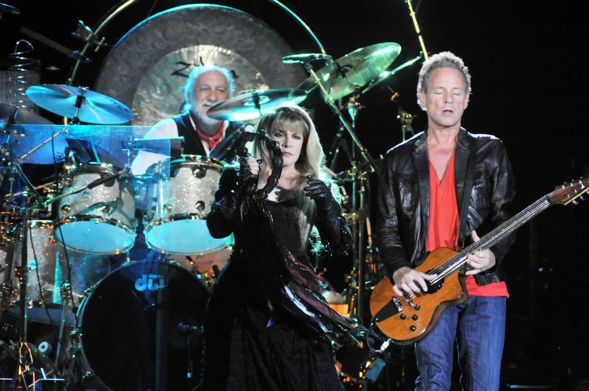 Mick Fleetwood drums from behind Stevie Nicks, who plays the tambourine, and Lindsey Buckingham who plays guitar.