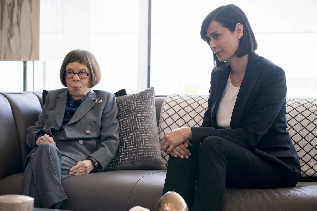 Linda Hunt and Catherine Bell sitting on a couch in front of windows in 'NCIS: Los Angeles'